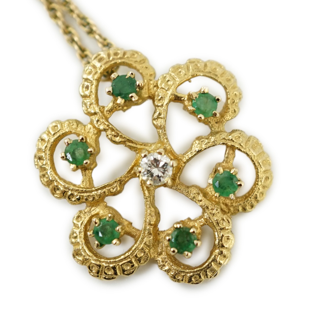 A modern yellow metal, emerald and diamond set stylised flower head pendant, 25mm, on a 375 chain, 46cm, gross weight 6.7 grams.
